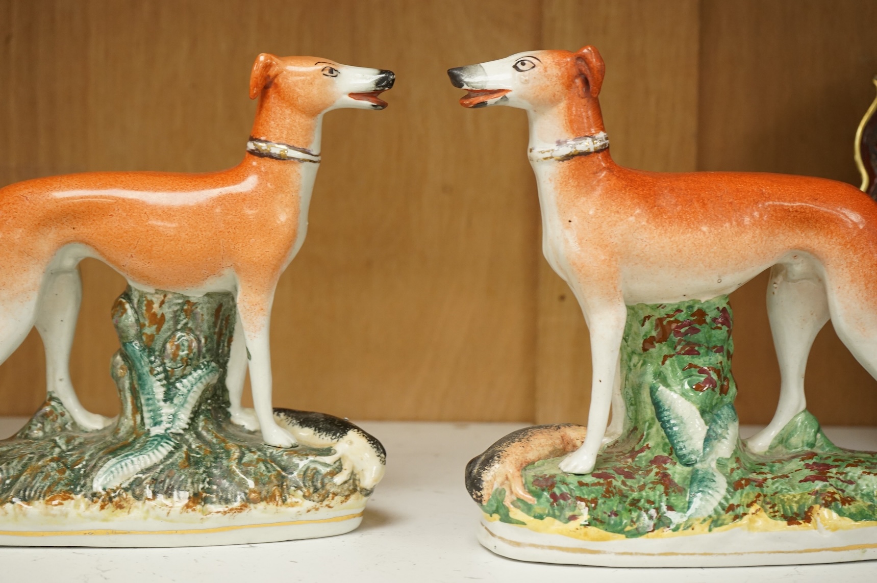 A pair of Staffordshire whippets, 19th century, one damaged, 19cm wide